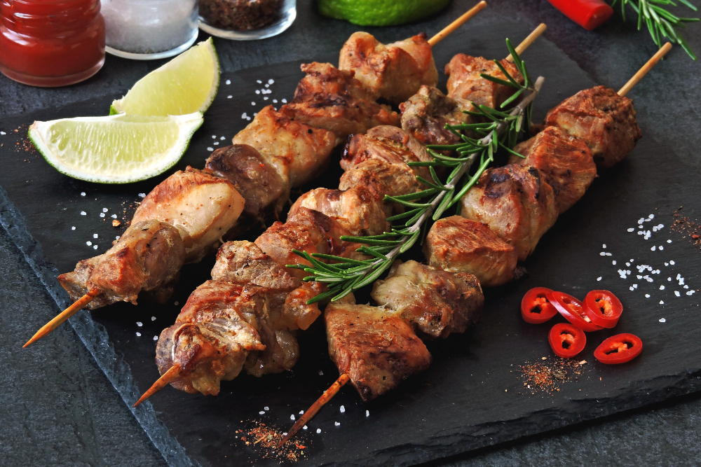 espetinho de carne no prato com decoração de tomate e pedaços de limão